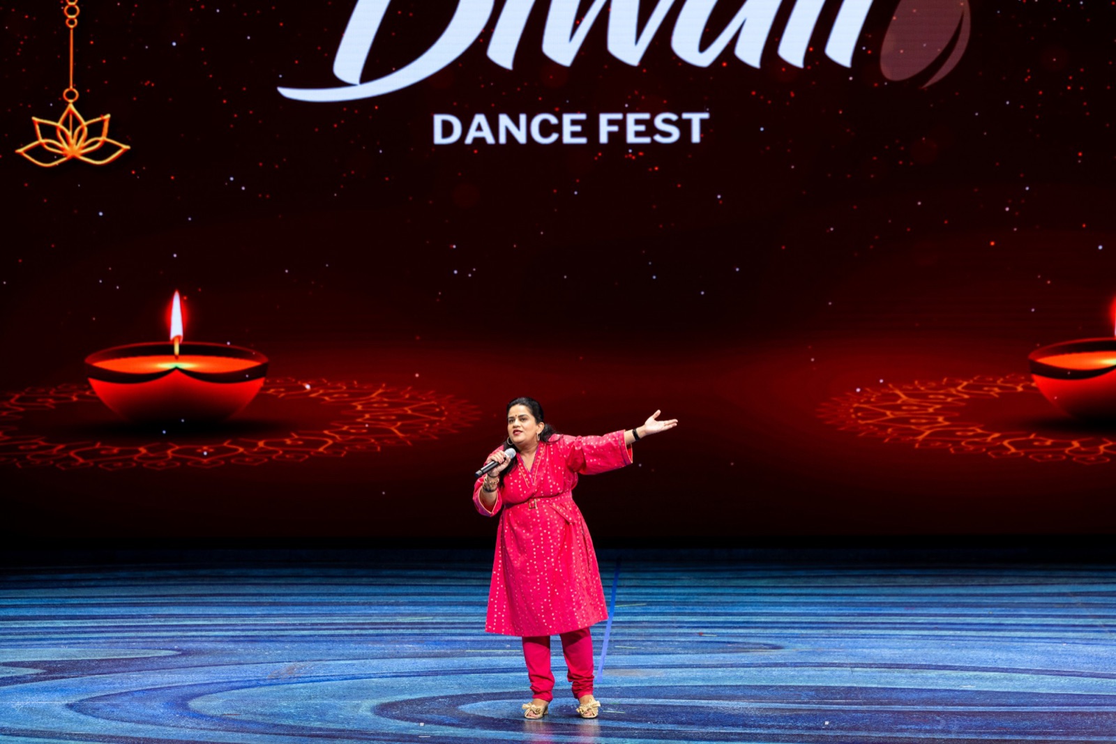 A performer with a microphone on the Diwali Dance Fest stage