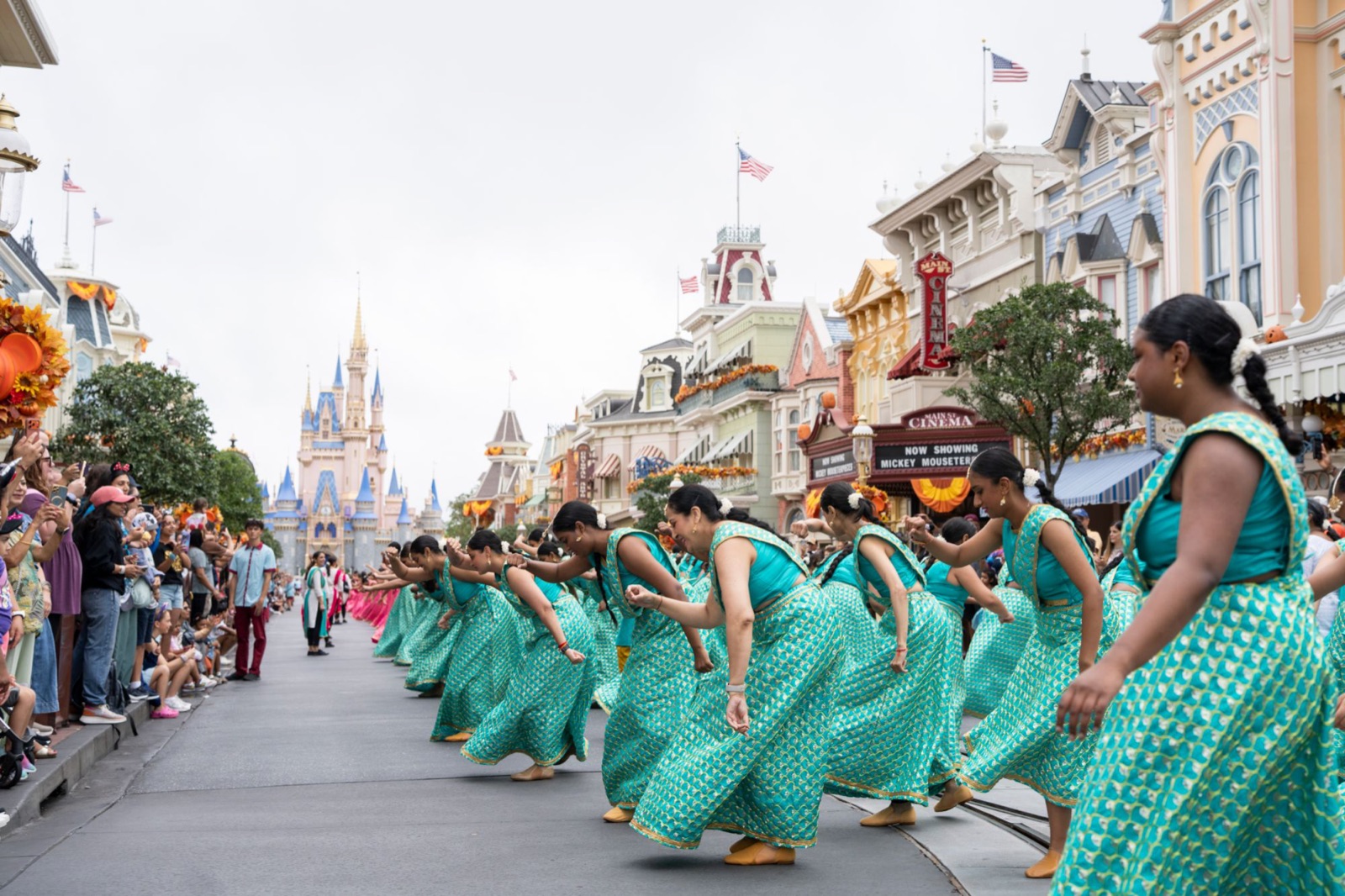 A line of dancers in teal performing on Main Street USA