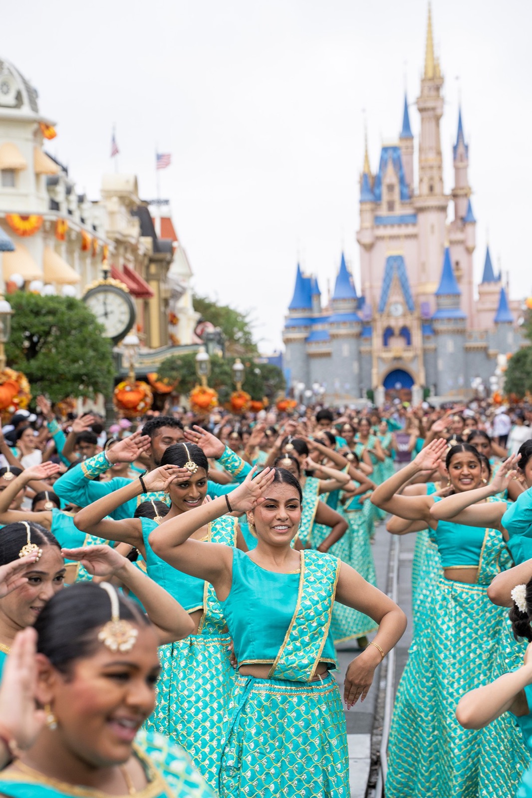 Smiling dancers in teal performing on Main Street USA